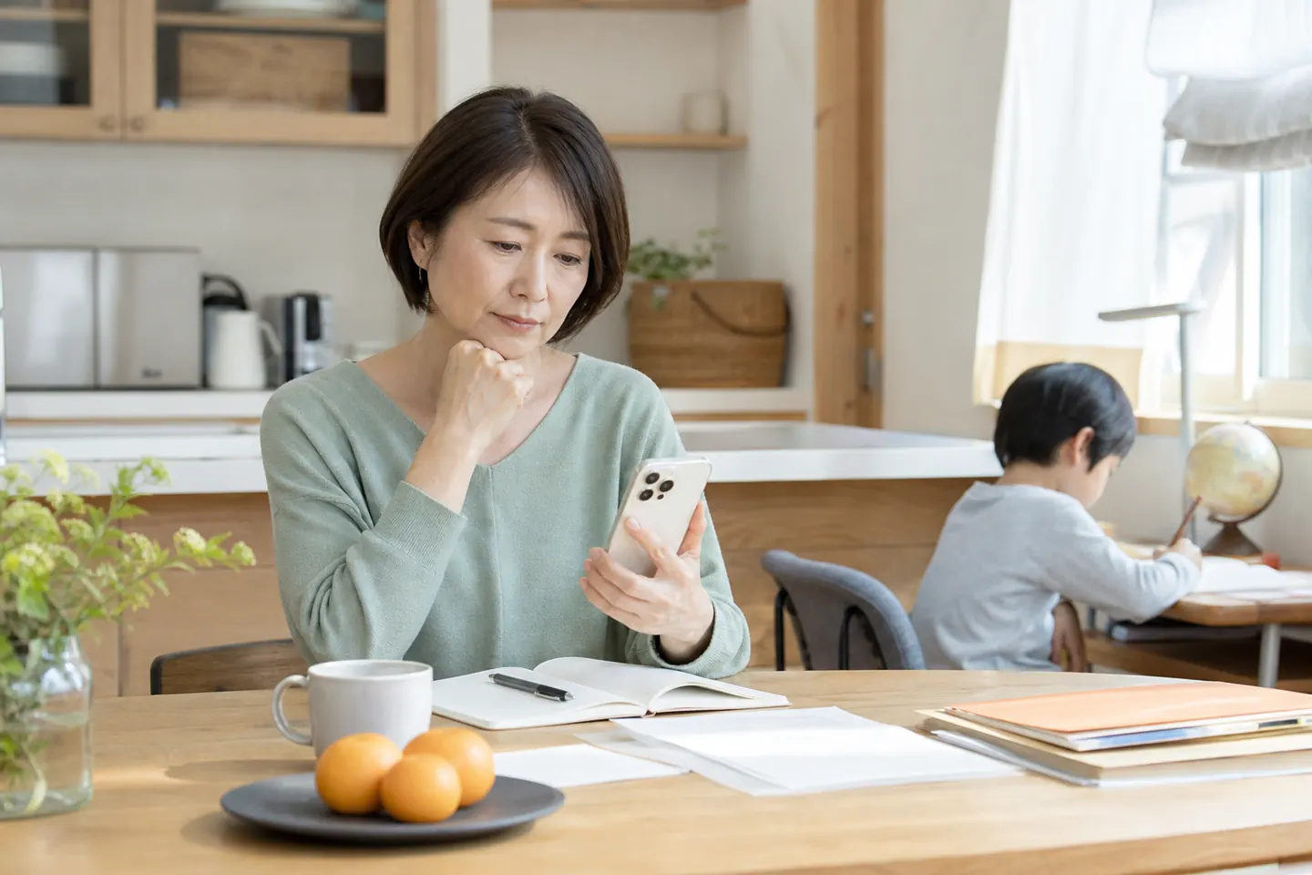 食卓で高齢の親への電話を考える50代女性